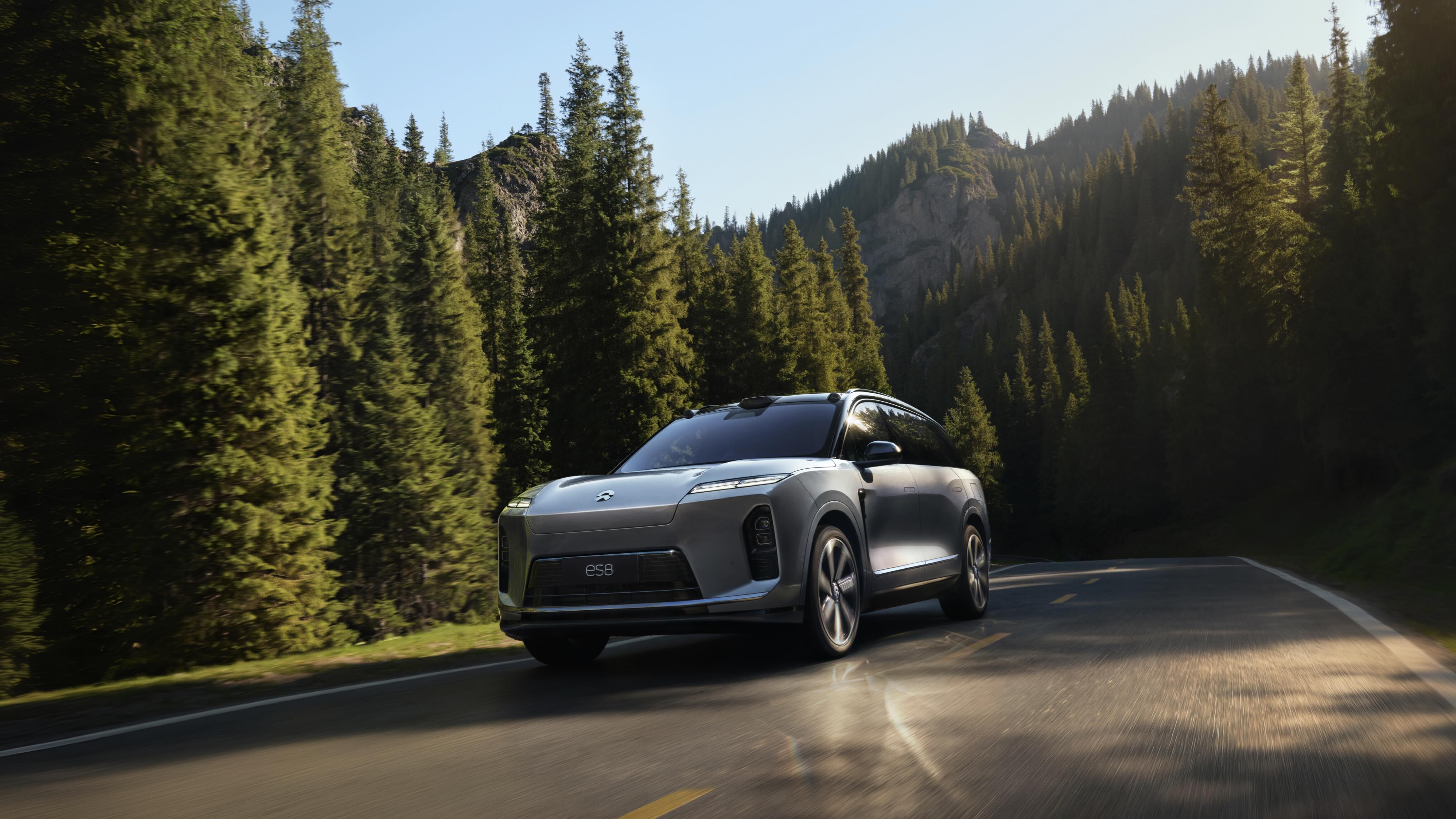 Silver 2026 NIO ES8 driving on a forest road, front three-quarter view